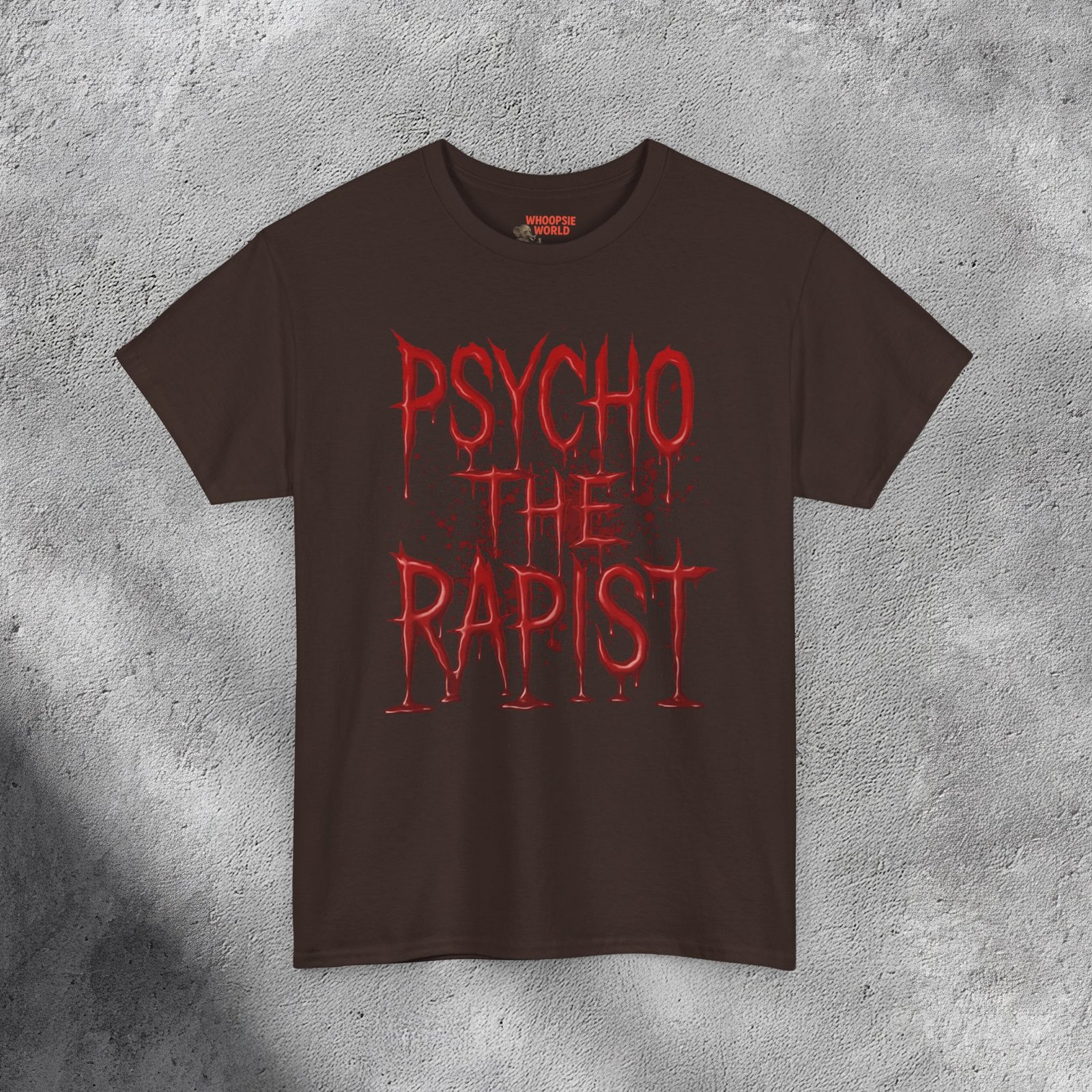 The T-shirt features bold, dripping red text reading “PSYCHO THE RAPIST” stacked in three lines against a dark black background. The letters appear glossy and wet, resembling fresh blood or thick paint, with realistic reflections and shadows adding depth. Behind the text, subtle red splatters and stains spread outward, enhancing the disturbing, horror-inspired aesthetic. The shirt’s fabric texture shows faintly beneath the design, making it feel gritty and raw — like a heavy metal or dark-humor statement piece with a shocking visual punch.
